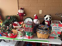Overview of assorted Christmas decorations labeled as top shelf items, featuring tins, wreaths, stuffed panda, ornaments, and some boxes stacked