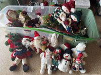 Tote full of various Christmas figurines including snowmen, Santa Claus, and holiday dolls in cloth, ceramic, and porcelain materials