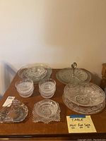 Cut glass serving set includes tiered tray with metal handle, bowls, platter, candy dish, and small individual bowls or cups.