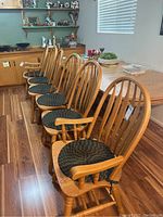Set of six wood dining chairs arranged in a row, showcasing the overall appearance and cushion colors.