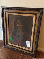 Framed portrait of a Native American man, showing the carved wooden frame and textured beige inner border.