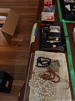 Photo showing assortment of six watches placed on table along with costume necklaces, Christmas pins, and a metal door hanging jewelry holder.