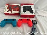 Photo showing red and black wired Nintendo Switch controllers in box along with two plastic replacement protective cases (blue and red).