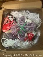 Photo of a box containing multiple sealed packs of women's undergarments in various colors such as white, purple, red and coral. Packages are bundled with green and white ties.