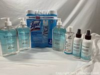 Three cans of Lysol Disinfectant Spray 3-pack with blue and white packaging, three large pump bottles of Live Clean Hand Sanitizer with blue liquid and three smaller spray bottles of Art Naturals hand sanitizer.