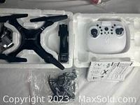 Overview photo of the drone body, remote controller, and accessories arranged in white foam packaging