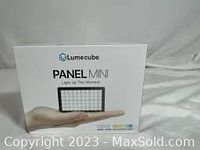 Front view of the Lume Cube Panel Mini box showing the product image and branding, held on an open hand.