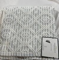 Folded bath towel showing textured geometric pattern and product tag.