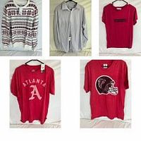 Image showing multiple clothing items hung on hangers against white background: knit patterned sweater, light blue pinstripe dress shirt, and four red t-shirts with Atlanta logos.