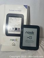 Barnes and Noble Nook Simple Touch eBook Reader beside original box showing device and packaging front.