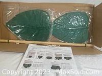 Two handcrafted cotton macrame monstera leaves in original plastic packaging inside a cardboard box.