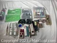 Lot contents including makeup items, creams, lip products, beauty blotters, headbands, and hair bands packed and arranged on a surface