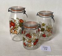Three vintage ARC France glass canisters with colorful garden vegetable patterns and hinged lids.