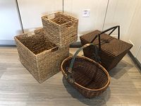 Photo showing all four baskets: two nesting water hyacinth baskets stacked inside each other, oval wicker basket with handle, rectangular wicker basket with metal handle and frame.