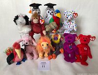 Photo showing 13 Beanie Babies including owls, monkey, toucan, bear, flamingo, poodle, lion, and colorful birds, all with original Ty tags.
