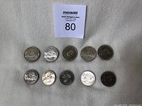 Overview of ten circulated Canadian silver dollars in two rows on fabric background