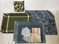 All items laid out showing placemats (Crate & Barrel, green woven, Pier 1 Imports), pot-holder, and doilies.