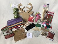 Image of miscellaneous craft supplies on white background showing foam sheets, pom-poms, paint brushes, glues, ribbons, and wooden shapes.