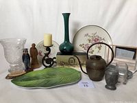 Photo showing entire collection of household decor items including Blue Mountain Pottery vase, decorative plates, melamine leaf tray, wooden carved figures, candlestick, and pewter cup.