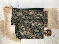 Photo showing floral tapestry placemats, green backing, large round crochet doily, and 8 wood raw edge napkin rings