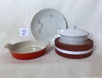 Front view of Le Creuset Heritage round baking dish, covered Brie baker, and decorative plate.