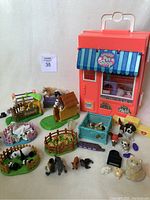 Overview photo showing the Littlest Pet Shop house, stable, various animal enclosures, and loose figurines arranged on a white surface.