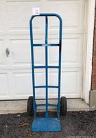 Front view of blue Mastercraft dolly standing upright with garage door background. Shows overall size and frame structure.