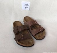 Front angle showing pair of men's brown Birkenstock sandals with two buckles each, slight color difference between the sandals.