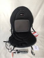 Full view of the ObusForme massage and heated car cushion with remote control and 12V adapter visibly attached showing the entire front of the cushion