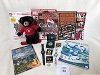 Full collection of Olympics memorabilia and collectibles including watches, pins, magazines, books, plush bear, and coin.