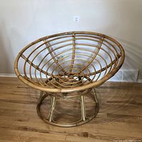 Front view of Papasan chair frame showing the circular bowl-shaped rattan seating area and base on hardwood floor.