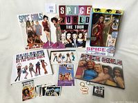 Full view of Spice Girls collectible items laid out including doll, books, posters, cards, keychains.