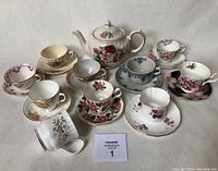 Eleven teacups arranged with ten matching or mismatched saucers and Sadler floral teapot visible.