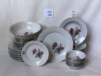 Full set of vintage East German dishes including stacked plates, bowls, and saucers with floral designs and gold trim.