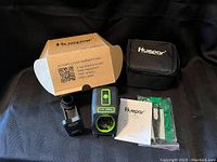 Shows the laser tool, carrying case, user manual, and packaging box laid out flat