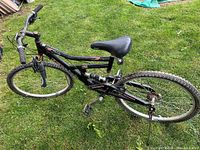 Black adult mountain bike with padded saddle, front and rear suspension, Shimano SIS 21-speed shifter, some rust visible