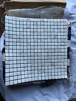White Carrara marble mosaic tile sheet showing small 5/8 inch squares laid out on 12x12 inch mesh sheet