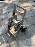 Photo showing front side of the plastic hose reel with wheels and crank handle, highlighting the overall shape and structure.