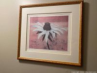 Image of the framed print hanging on a wall showing the full artwork, matting, and frame with visible gold-toned color and ornate edge. Shows an overall view of the item.