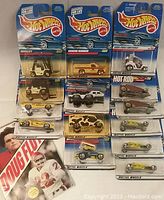 Photo showing 14 Hot Wheels die-cast cars in original sealed blister packs from 1997-1999 plus a Doug Flutie football book