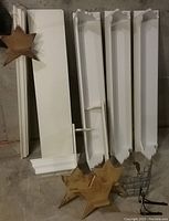 White Pottery Barn floating shelves and regular wall mount shelves alongside custom wood star shelves and metal brackets arranged flat on floor.