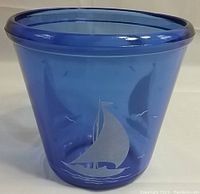 Front view of the cobalt blue glass ice bucket with etched sailboat and seagull design, showing shape and color.