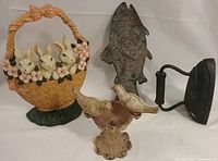 Photo showing the metal bunny basket doorstop with four bunnies, antique sad iron, heavy metal bird bath with two birds, and fish trivet, all metal items on a white surface.