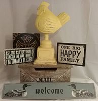 Photo shows six wooden decorative items including large yellow chicken statue, wooden mail box, loon welcome sign, and three smaller wood signs with different texts and designs.