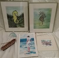 Full lot of six sea art related items including the two framed seahorse prints, two loose signed prints, glass dolphin figure, and wooden boat.