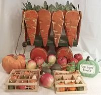 Front view of wooden carrot wagon with faux vegetables including resin pumpkins, plastic apples, and carrots, plus two crates of ceramic vegetables displayed in front