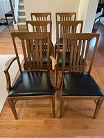 Front view of all six oak dining chairs, five armless and one with arms