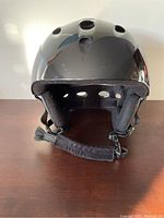Black ski helmet front view showing ventilation holes and chin strap.