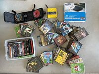 Top-down view showing approximately 40-50 DVDs spread out with some in cases and sleeves plus a new Samsung Blu-ray DVD player in sealed box.