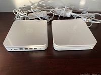 Two white square Apple AirPort WiFi modems with visible Ethernet ports and Apple logos